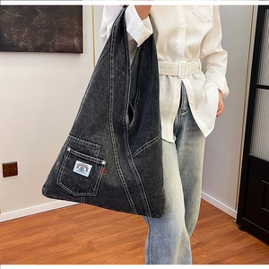 Detail view of washed denim hobo bag featuring contrast stitching and side pocket design