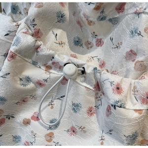 Detailed macro view of floral lace fabric featuring an adjustable white drawstring toggle