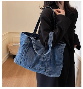Detail of blue denim tote bag showing stitching and functional front pocket