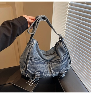 Detailed close-up of a blue denim hobo bag featuring retro wash and silver metal buckles
