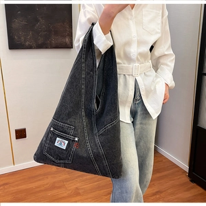 Detail of vintage denim crossbody bag featuring white contrast stitching and logo patch