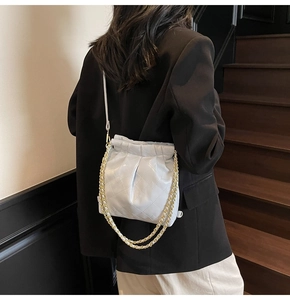 Detail view of light blue quilted leather cloud bag with gold chain strap on a model