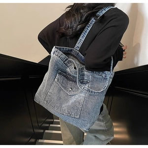 Detail of vintage blue denim tote bag showing decorative pocket and metal button