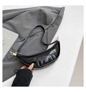 Detail of glossy black crescent bag with sleek gold zipper and wrinkled patent leather finish