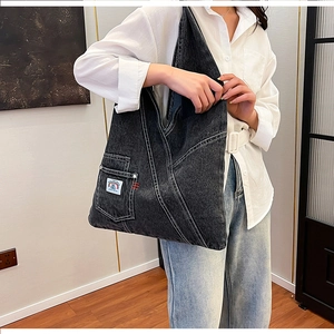 Detail view of large grey washed denim tote bag with side pocket and colorful embroidery