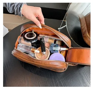 Top view of open brown leather makeup bag showing spacious interior with cosmetics