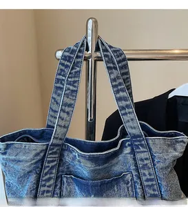 Detail of wide shoulder straps and durable blue washed denim texture on tote bag