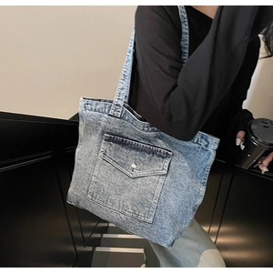 Detail of vintage denim tote bag featuring front pocket with metal button on steps