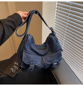 Detailed view of dark denim motorcycle bag with silver buckles and flap pockets