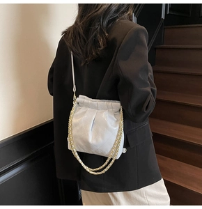 Rear view of a model wearing a light blue quilted crossbody bag with gold chain details