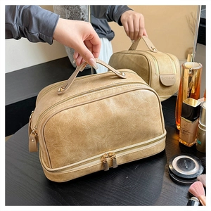 Detail view of large capacity cream makeup bag with dual zippers and leather texture