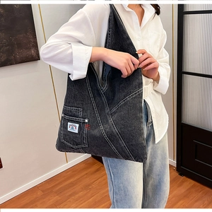 Detail view of large dark grey washed denim tote bag showing stitch pattern and label