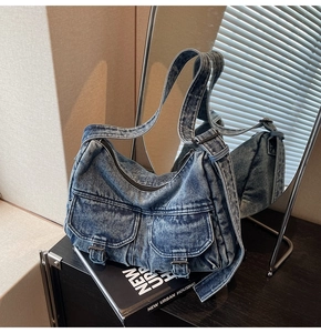 Macro detail of retro acid wash denim motorcycle bag with dual front pockets and metal buckles
