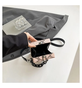 Detail of pink snakeskin pattern small box bag with chunky black chain handle and clasp