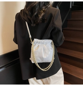 Close-up of quilted bucket bag featuring glossy finish and gold chain strap detailing