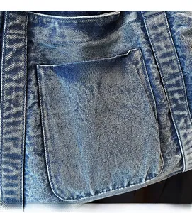 Macro shot of blue washed denim bag featuring detailed stitching and outer pocket texture