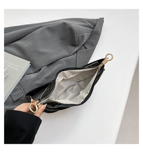 Detail view of the black dumpling bag showing its textile lining and golden metal clasp