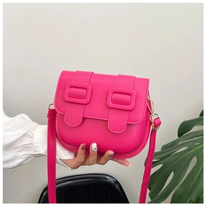 Détail d'un mini sac selle rose vif avec boucles métalliques et bandoulière réglable