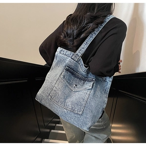 Detailed view of retro washed blue denim tote bag worn on shoulder by model
