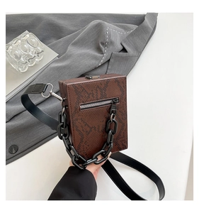 Detailed view of a brown snakeskin pattern box bag with acrylic chain and silver zipper