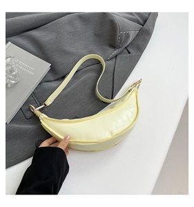 Detail of light yellow crescent shoulder bag with smooth faux leather texture and gold zipper