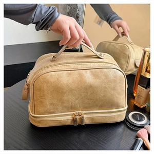 Detailed close-up of large capacity beige leather toiletry bag with golden metal zippers