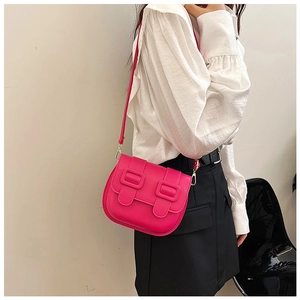 Gros plan d'un sac besace rose fuchsia avec boucles porté par un mannequin en chemisier