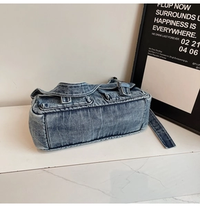 Detail of vintage washed blue denim shoulder bag with multi-pockets and retro buckle