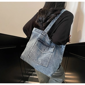 Detail shot of the large front pocket and washed denim texture of the tote bag
