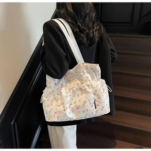 Detailed shot of the floral canvas tote bag featuring side drawstring pockets and wide straps