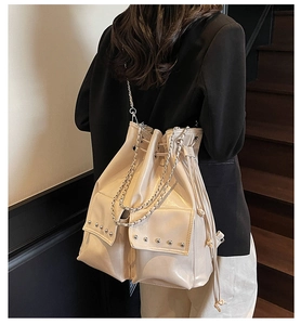 Detailed view of beige waterproof studded bucket bag with chain strap on a shoulder