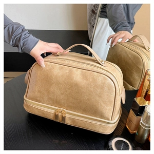 Close-up of beige double-layer makeup bag showing lychee leather texture and gold zippers