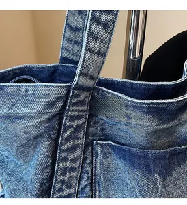Close-up of reinforced cross-stitching and outer pocket on a vintage blue denim handbag
