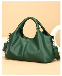 Close-up of dark green leather handbag showing woven handle and pleated texture detail