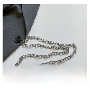 Detail of silver metal chain strap and white lychee texture leather on a mini crossbody bag