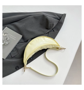 Close-up of a pale yellow crescent bag with smooth leather and gold metal hardware