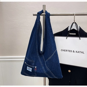Close-up of deep blue denim shoulder bag with white stitching and front patch pocket