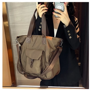 Detail view of large nylon tote bag in olive brown with front flap pocket and chain detail