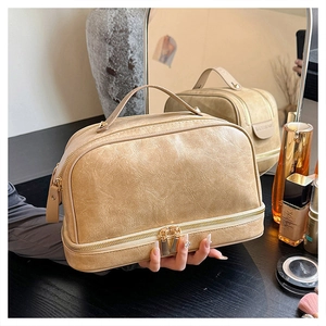Detail view of khaki PU leather makeup bag with double gold zippers and sturdy top handle