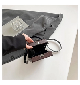 Macro view of dark brown snakeskin embossed box bag with silver buckle and black lining