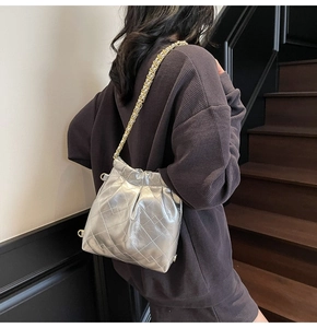 Detail of silver quilted bucket bag with metallic finish and gold-silver chain strap