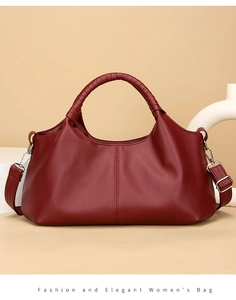 Detail of burgundy pebbled leather texture on tote bag with woven handles and silver hooks