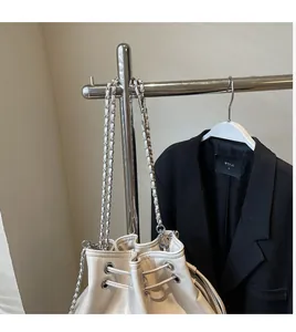 Detail of cream bucket bag showing metal ring eyelets and woven chain shoulder strap