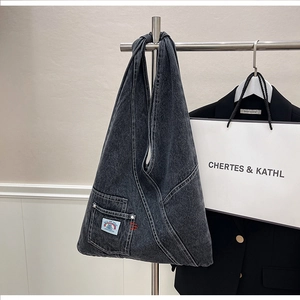 Detail of grey denim hobo bag featuring a small rainbow pocket and Into the Space label