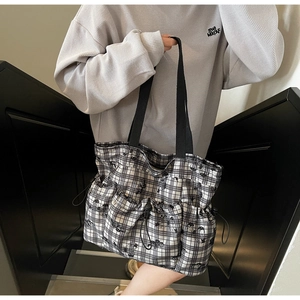 Detail of black and white checkered tote bag with drawstring pockets and wide straps