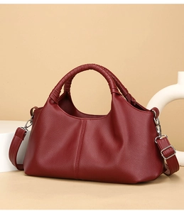 Detailed close-up of dark red pebble leather handbag with premium metal buckles and handle