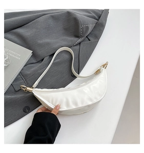 Detailed view of white crescent bag showing synthetic leather texture and golden hardware