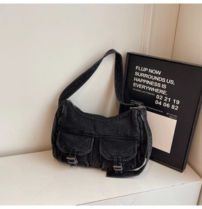 Detail view of black denim motorcycle bag with dual front pockets and silver buckles