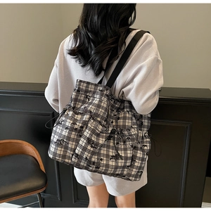 Detail of checkered tote bag with side drawstring pockets and durable wide strap