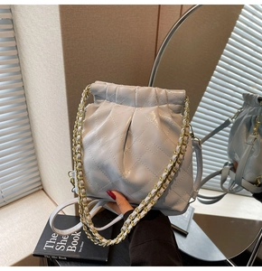 Detail of light blue quilted leather bag with gold chain strap and drawstring closure